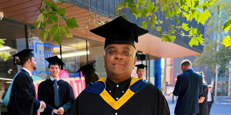 Romesh Dodangoda wearing Graduation cap and gown outside Leeds Conservatoire entrance
