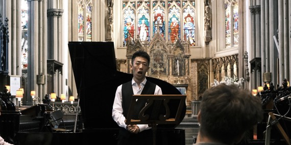 Image: student singing in front of stained glass window
