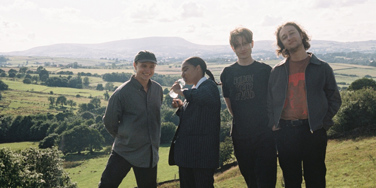 Four-piece band English Teacher stood in a line in countryside setting