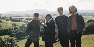 Four-piece band English Teacher stood in a line in countryside setting